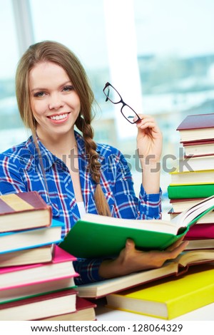 Portrait of diligent student looking at camera with open book in hands