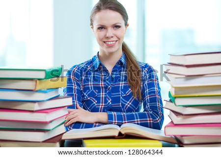 Portrait of diligent student looking at camera with open book near by