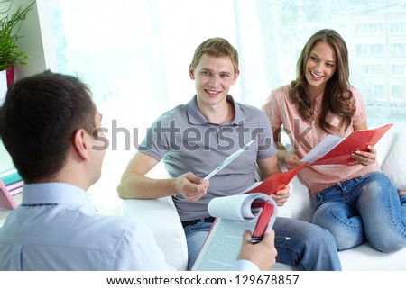 Manager and his cheerful clients discussing the most profitable insurance program for a young family