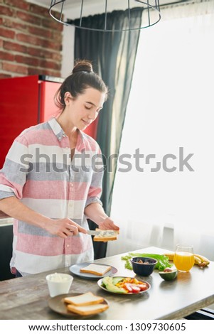 Waist up portrait of smiling young woman cooking healthy breakfast in modern apartment