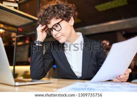 Pensive analyst touching her forehead while trying to concentrate on reading online information