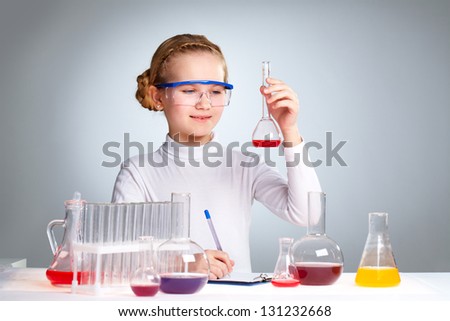 A little girl looking at chemical sample in a flask