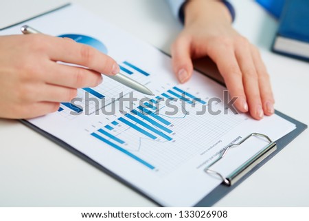 Close-up of printed statistics analyzed by a female business worker