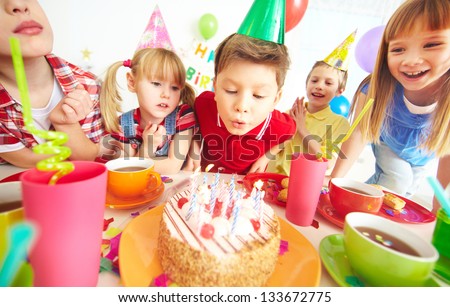 Group of adorable kids gathered around birthday cake with candles
