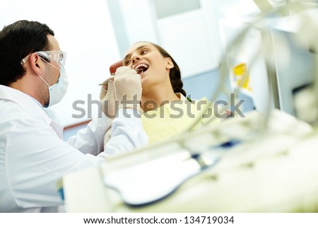 Young woman sitting in dentistÃ?Â¢??s chair while doctor examining her teeth