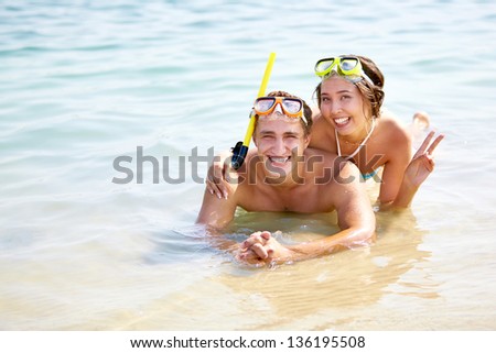 Copy-spaced portrait of smiling young people in scuba masks lying in water