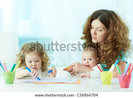 Beautiful mother showing her children how to draw