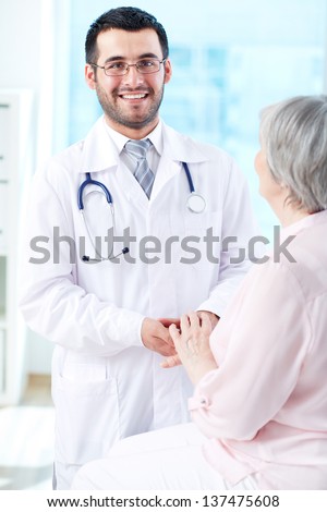 Confident doctor with senior patient looking at camera with smile