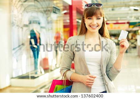 Pretty lady with shopping bags showing credit card