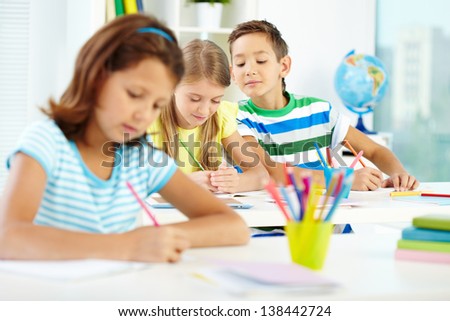 Group of cute schoolkids drawing at lesson