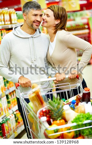 Image of happy couple with cart flirting in supermarket
