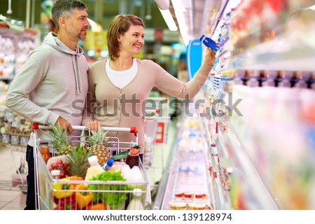Image Of Happy Couple With Cart Choosing Products In Supermarket
