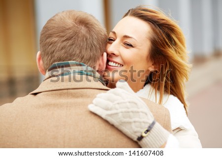 Portrait of happy girl embracing her sweetheart and whispering something into his ear