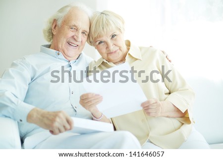 Portrait of a candid senior couple with paper looking at camera