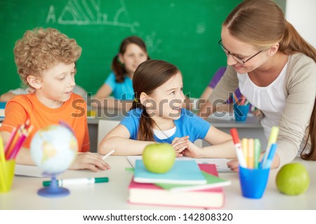 Portrait of diligent schoolkids and teacher interacting at lesson