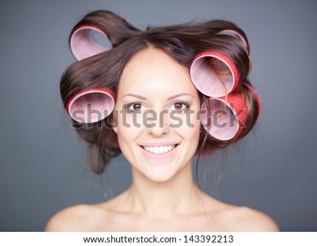 Close-up of happy woman with hair-rollers looking at camera