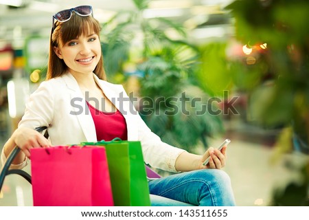Pretty lady with colorful shopping bags sitting in trade center