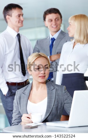 Pretty businesswoman looking at laptop display with several partners on background