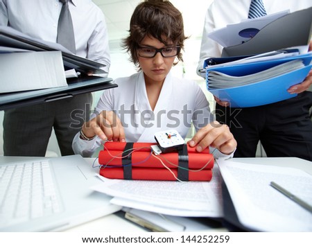 Serious secretary with dynamite being surrounded by big heaps of papers held by men