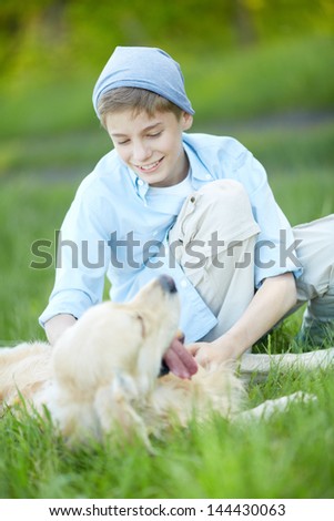 Portrait of cute lad cuddling his fluffy friend while lying on grass