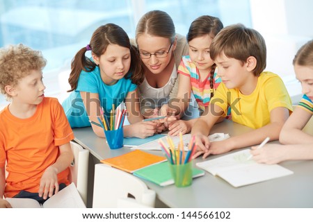 Portrait of diligent schoolkids and their teacher interacting at lesson