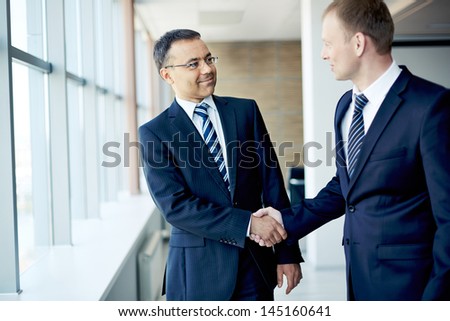 Portrait Of Elegant Businessmen Handshaking In Conference Hall