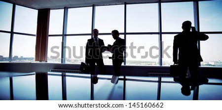 Business people spending a usual busy day in office, only silhouettes being recognizable