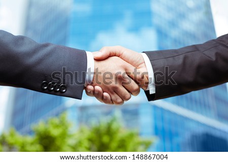 Close-up of business people handshaking on background of modern building