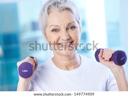 Portrait Of Pretty Senior Woman Exercising With Dumbbells