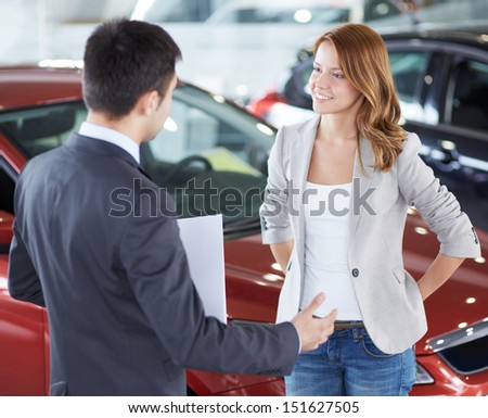 Image of car dealer and happy female communicating in automobile center