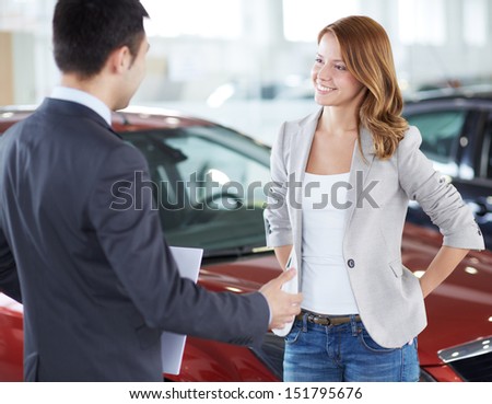 Successful young lady discussing her potential purchase with a car dealer