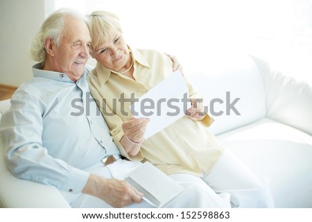 Portrait of a candid senior couple sitting and reading letter