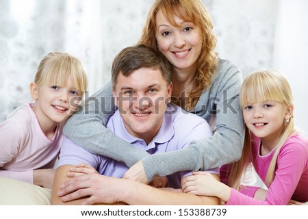 Portrait of wife hugging her husband with their daughters near by