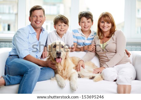 Cheerful family with their pet sitting on sofa at home