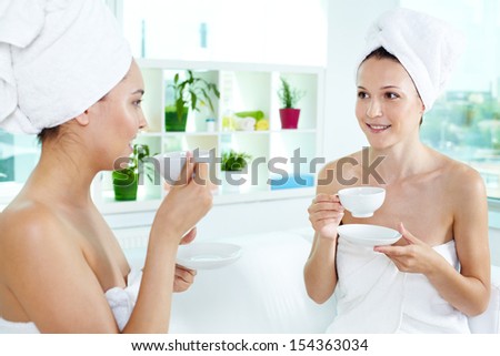 Girls in bath towels communicating in spa salon while drinking tea