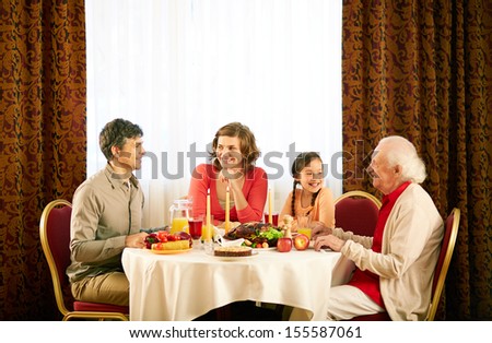 Portrait of happy family sitting at festive table and having Thanksgiving dinner