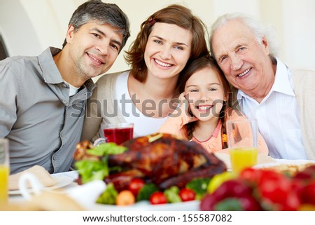 Portrait Of Happy Family Sitting At Festive Table And Looking At Camera