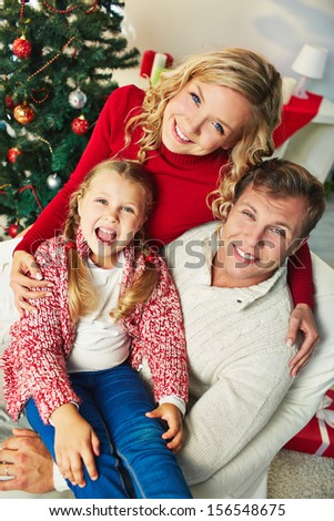 Portrait of happy family of three looking at camera on Christmas day