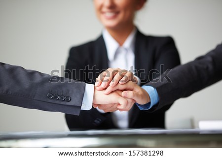 Image of pile of hands of business partners on background of businesswoman