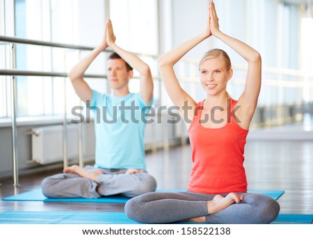 Portrait of healthy girl and guy doing exercise for relaxation in gym