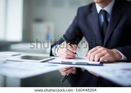 Close-up of male hands with pen over document