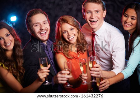 Group of joyful friends toasting with champagne in the bar