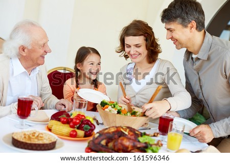 Portrait Of Happy Family Sitting At Festive Table While Having Thanksgiving Dinner