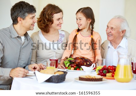 Portrait of happy family sitting at festive table and having Thanksgiving dinner