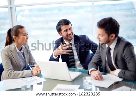 Portrait Of Three Co-Workers Discussing Business Plan In Office