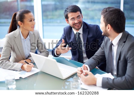 Portrait Of Three Happy Co-Workers Interacting At Meeting In Office