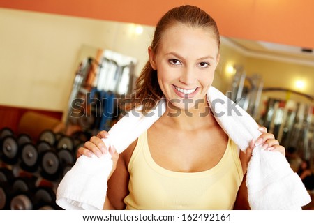 Portrait of pretty girl with towel looking at camera in gym