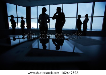 Silhouettes of several colleagues communicating in office