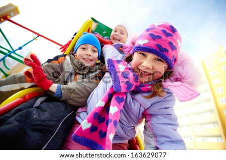 Happy girl in winterwear playing outside with her friends on background
