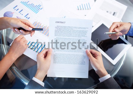 Image of human hands during discussion of contract at meeting